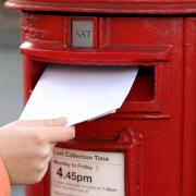 posting letter to red british postbox on street