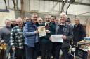 Keith Ellwood (left) and John Cadwallader (right) present the cheque to Shed supervisor Ed Carswell and members