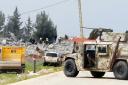 A Lebanese army vehicle blocks a road leading to a warehouse which was destroyed by Israeli air strikes (AP)