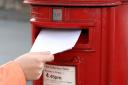 posting letter to red british postbox on street