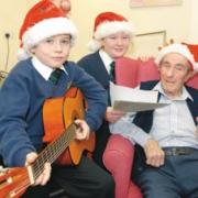 Musical treat: Pupils, Ryan Harper, 9 and Meghan Turner,10, entertaining nursing home resident, Tom Michael. Buy photo: 510933M