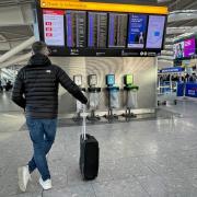 A man with a suitcase looking at the flight information in an airport. Credit: PA