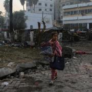 A Palestinian girl carries a blanket as she walks past the site of a deadly explosion at al Ahli hospital, in Gaza City