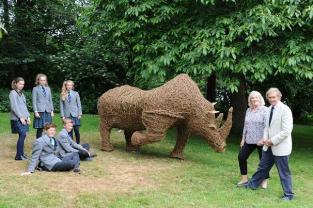 PECULIAR PRESENT: John Walker, right, and wife Janie, with some of the final year pupils who helped to create a wicker rhino statue.